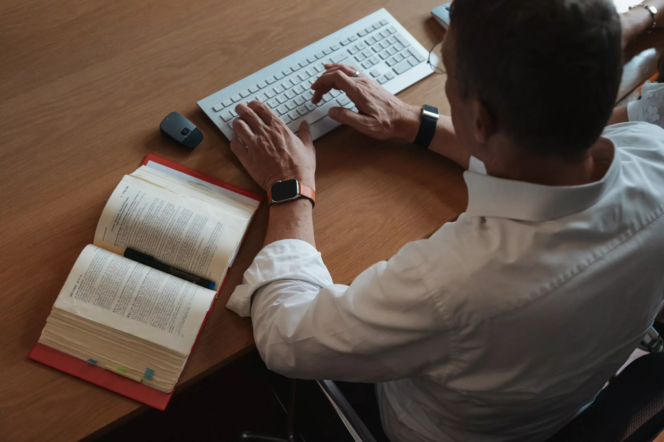 Mann tippt auf Tastatur mit offenem Buch